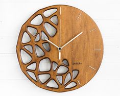 a wooden clock with holes in the middle on a white wall behind it is an abstract design