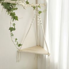 a white shelf hanging from the side of a wall next to a window with ivy growing on it