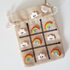 a cross stitch bag with rainbows, clouds and bears on the front is hanging from a string