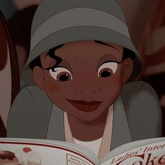 a young boy reading a book while wearing a hat