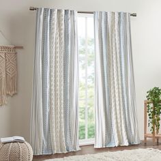 a living room with white and blue striped curtains, rugs and a wooden chair