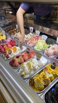 a display case filled with lots of different types of ice creams and toppings