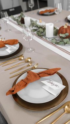 the table is set with gold and white plates, silverware, and napkins