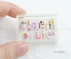 a hand holding a small plastic box filled with miniature items