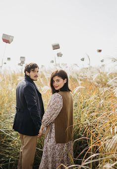 a man and woman standing in tall grass