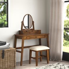 a wooden dressing table with a mirror and stool in front of a curtained window