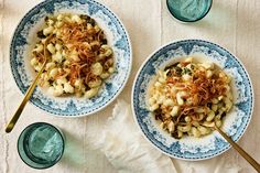 two blue and white bowls filled with food on top of a table next to glasses