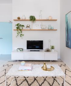 a living room filled with furniture and a flat screen tv on top of a white coffee table