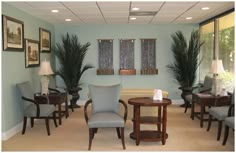 a living room filled with lots of furniture next to tall windows and potted plants