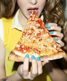 a woman holding a slice of pizza up to her mouth