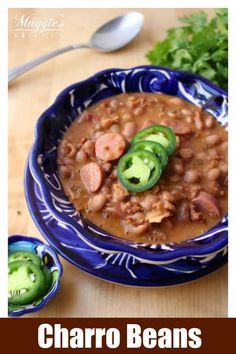 a blue bowl filled with beans and vegetables next to a spoon on top of a wooden table