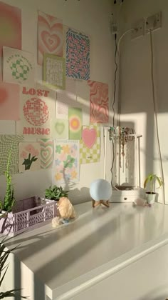 a white dresser topped with lots of art on the wall next to a planter