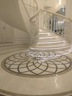 a spiral staircase in an elegant home with marble floors and white railings on the second floor