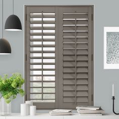 the interior of a living room with wooden shutters on the doors and table in front of it