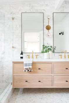 a bathroom with two sinks and mirrors on top of the counter, in front of a large mirror