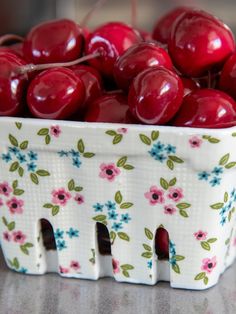 a bowl full of cherries sitting on a table