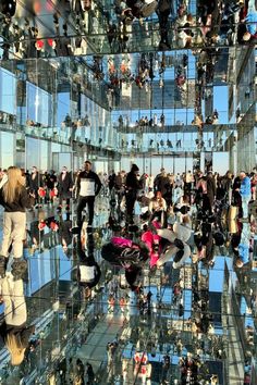 many people are reflected in the glass walls of a building with lots of mirrors on it