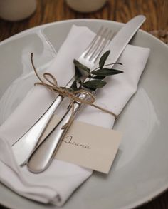 a white plate topped with silverware and a napkin tied around it's edge