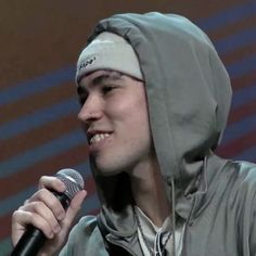 a young man wearing a hoodie holding a microphone