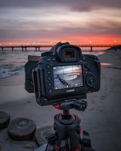 a camera is set up on a tripod to record the sunset at the beach