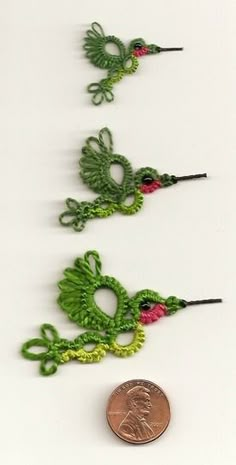 three crocheted dragon ornaments next to a penny on a white surface, one is green and the other is red