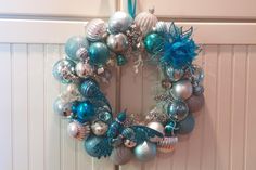 a christmas wreath hanging on the front door decorated with blue, silver and white ornaments