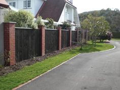 a residential street lined with houses next to a fenced in yard and grass area