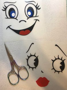 the scissors are next to some cut outs with eyes and eyelashes on them, as well as a pair of scissors