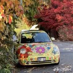 a colorful car is parked on the side of the road in front of some trees