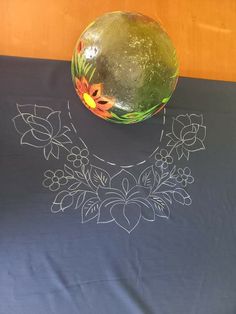 a watermelon sitting on top of a table next to a vase with flowers painted on it