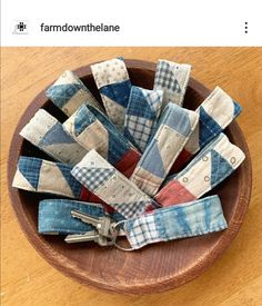 a wooden bowl filled with patchwork fabric and key fobs on top of a table