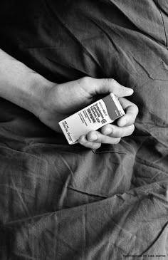 a person is laying on a bed with their hand holding an empty medicine bottle in black and white