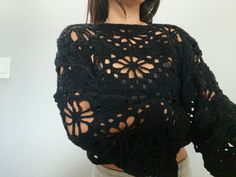 a woman wearing a black crochet top with cutouts on the back and shoulders