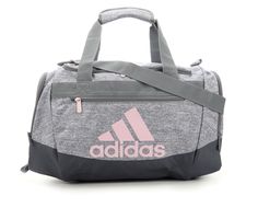 Just throw your gear in and head out with adidas' Defender IV Small Duffle Bag. From team meets, workouts at the gym, or even if you're just packing for a little weekend trip, this bag can handle it! Adjustable and removable nylon shoulder strap, Dual carry handles with padded grip, Large main compartment with dual zipper closure and internal zippered pouch,2 zippered side pockets and front zippered pocket for added storage, Approx. 18 inches W x 11 inches H x 8 1/2 inches D, adidas® branding details | Unisex Adidas Defender IV Small Duffel Bag in Jersey/Grey/Pink Adidas Duffle Bag, Pink Volleyball, Volleyball Bag, Small Duffle Bag, Pink Jersey, Justice Clothing, Athletic Accessories, Bags Aesthetic, Travel Duffel