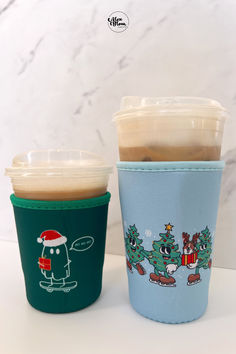 two coffee cups sitting next to each other on a white counter top, one has a christmas tree and the other has a santa clause on it