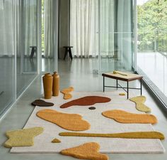 an area rug with various shapes and sizes on the floor in front of a glass wall