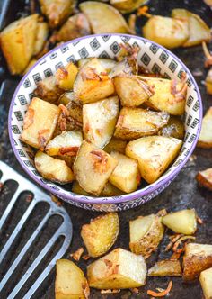 a bowl filled with cooked potatoes on top of a table next to a spatula