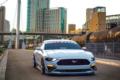 a white car parked on the side of a road in front of some tall buildings