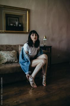 a woman sitting on top of a couch next to a mirror