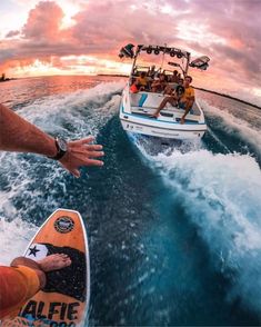 two people are riding in a boat on the water while another person holds out their hand