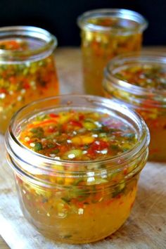 four jars filled with food sitting on top of a wooden table