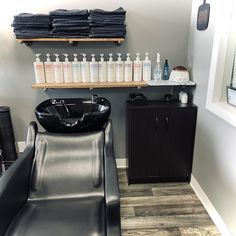 a black sink sitting next to a hair dryer on top of a wooden shelf