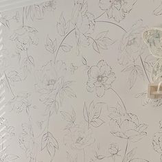 a white wall with flowers on it next to a light switch