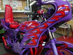 a purple motorcycle with red flames painted on it's front tire and seat cover