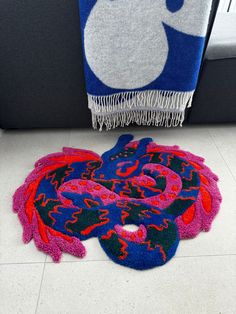 a colorful rug on the floor next to a blue and red towel with an image of a dragon