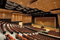 an empty auditorium with rows of seats in front of the stage and wooden walls on both sides