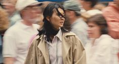 a blurry photo of a woman walking in front of a crowd with people behind her