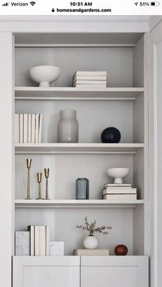 a white book shelf with books and vases on it