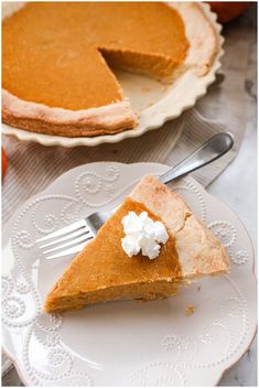 a slice of pumpkin pie on a white plate with a fork next to the pie