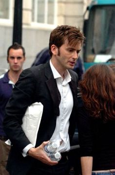 a man in a tuxedo is talking to a woman on the street, with caption buttons cannot contain hotness that is david tennant